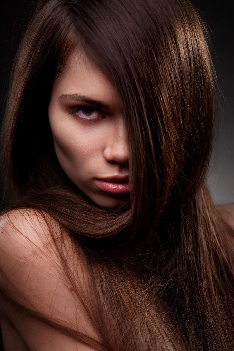 在工作室黑色背景下的年轻迷人的长头发的女人