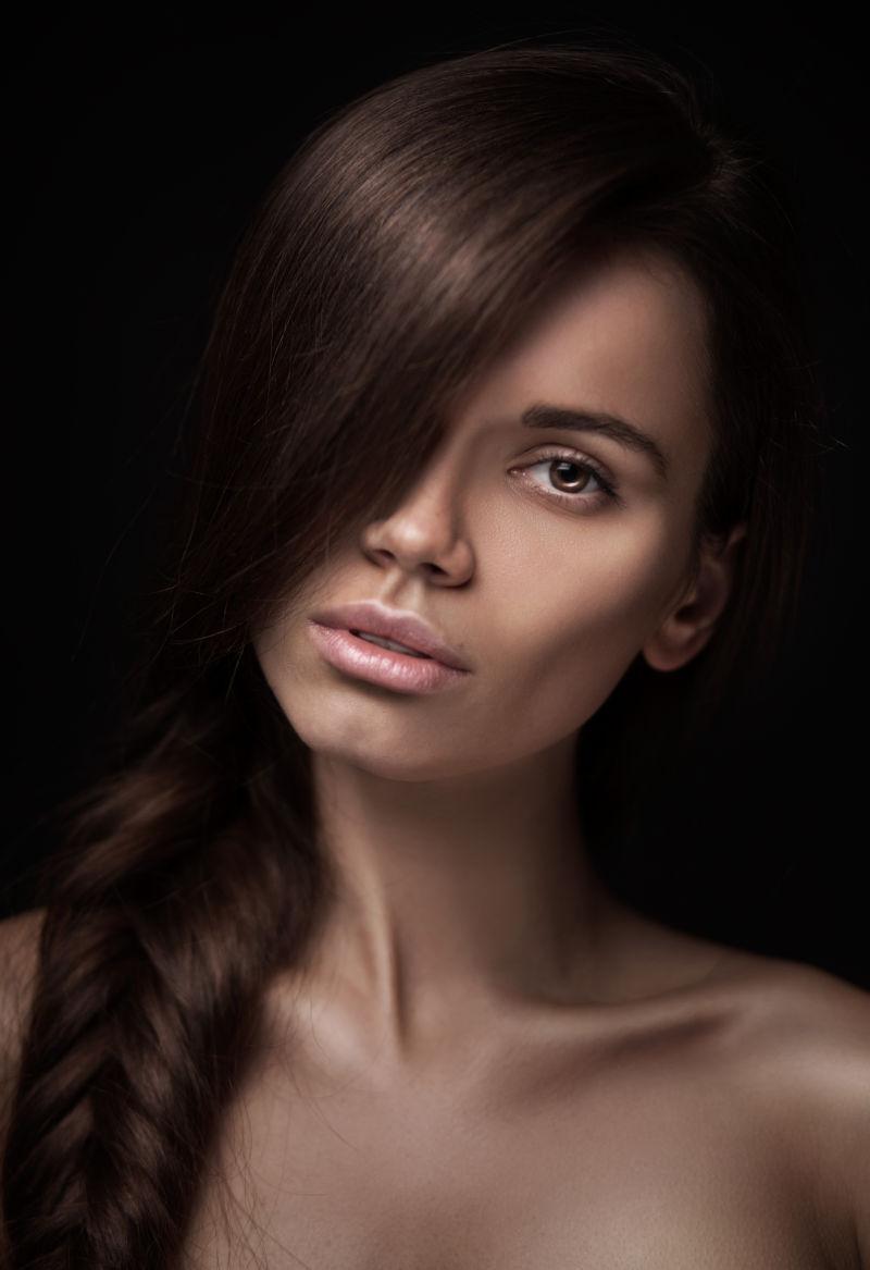 黑色背景下留着长长的黑色头发的美丽的年轻女子