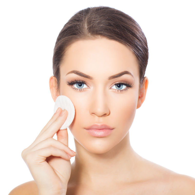 用白色的棉垫在脸上化妆的美女