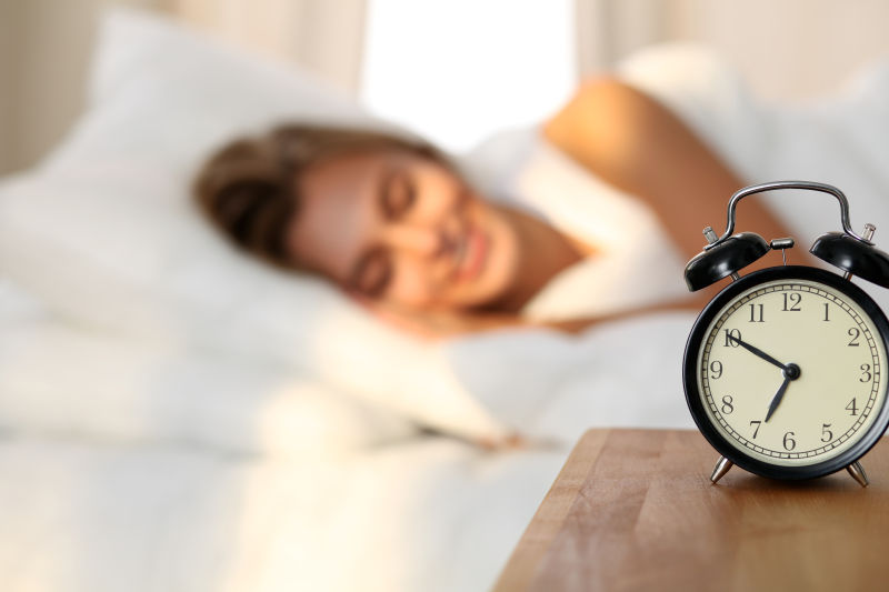 桌子上的闹钟和微笑睡觉的美女