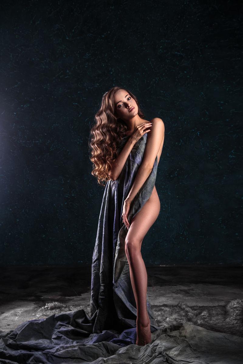 用灰色的布遮盖身体的长卷发性感美女