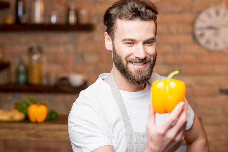 一个健康的男人在厨房里看黄胡椒的肖像
