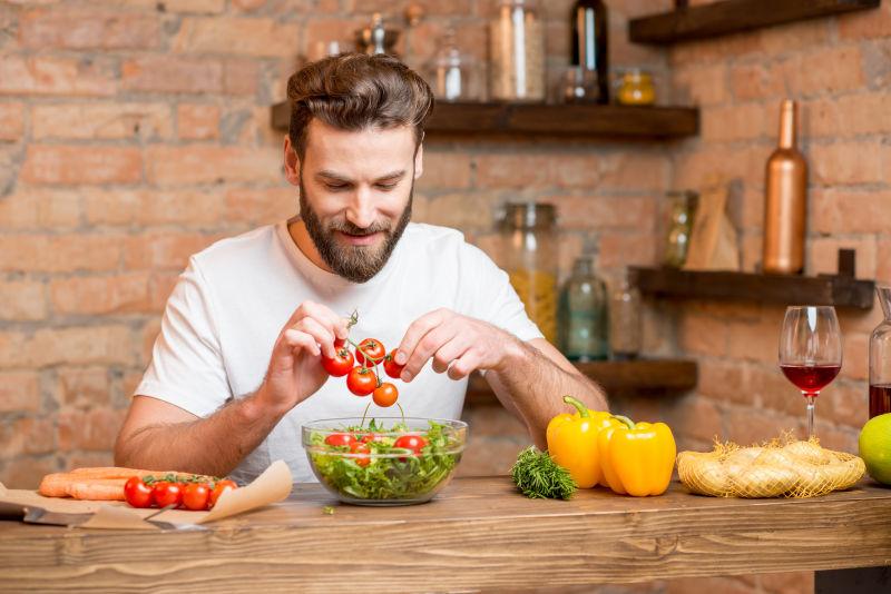 男人在厨房里做西红柿和胡椒沙拉