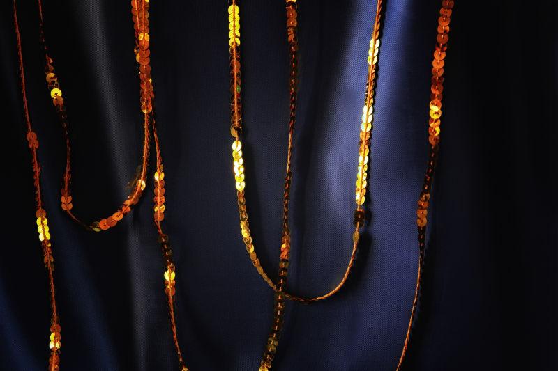 深蓝色丝绸背景下的金色闪光亮片配饰