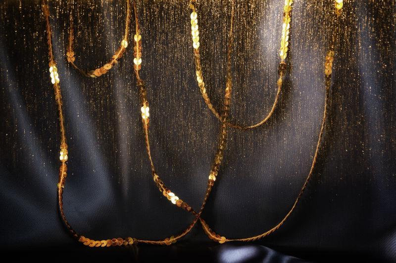 黑色丝绸背景下的金色闪光亮片