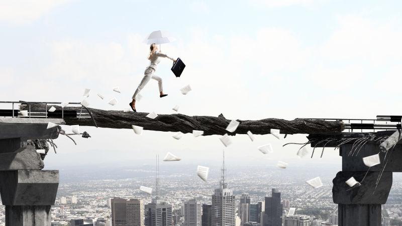 优雅的女商人带着伞在独木桥上前进