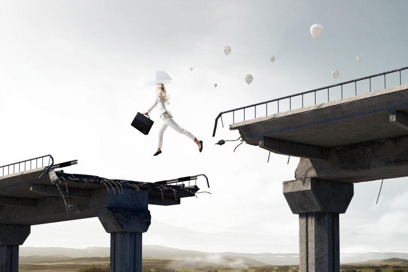 优雅的女商人带着伞飞过断裂的大桥