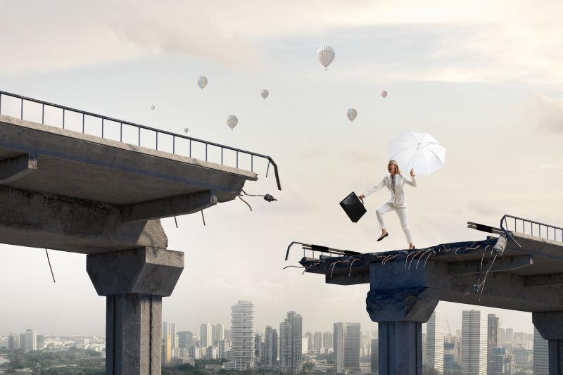 女商人手拿雨伞跨越断桥的挑战概念