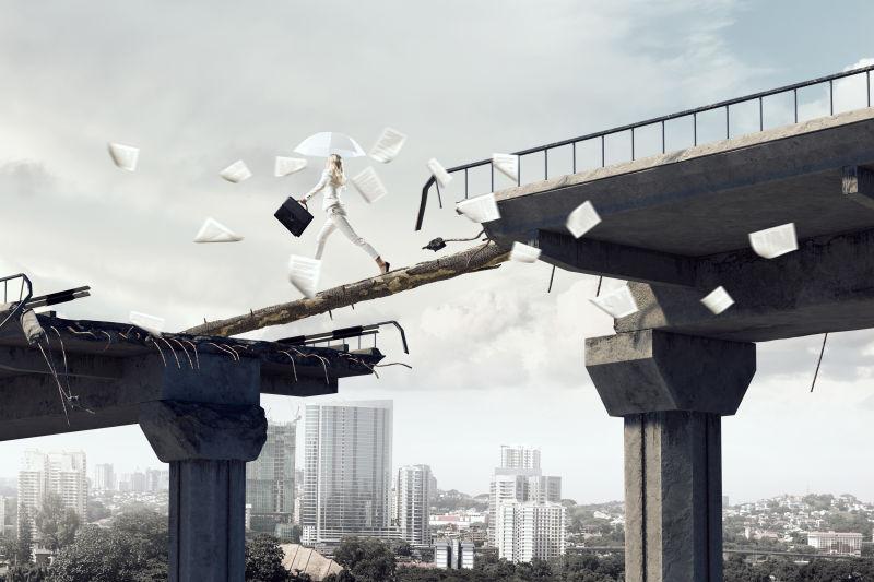 撑着伞的优雅的女商人在断桥的独木上行走