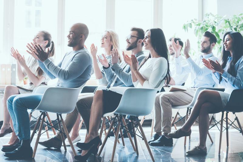 一组年轻欢快的人坐在一起开会鼓掌