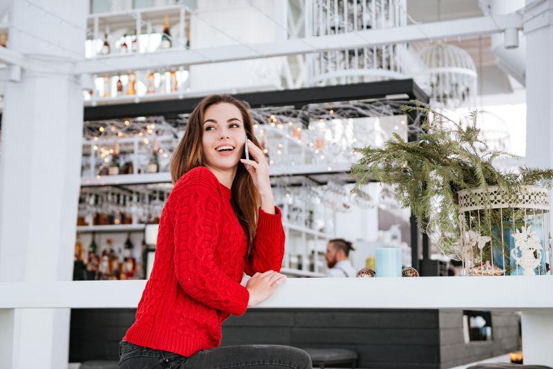 咖啡馆里讲电话的红毛衣年轻美女
