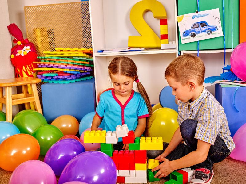 小男孩和女孩在幼儿园的地板上玩游戏