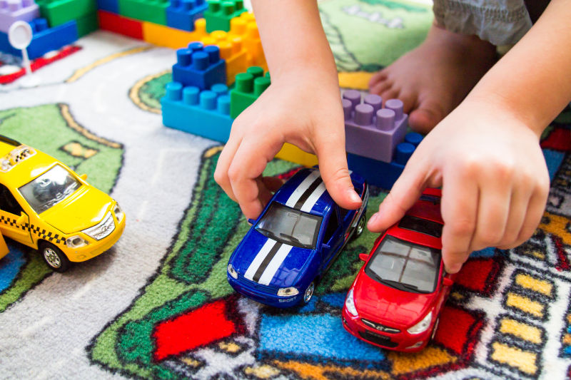 小孩在地毯上玩玩具小汽车