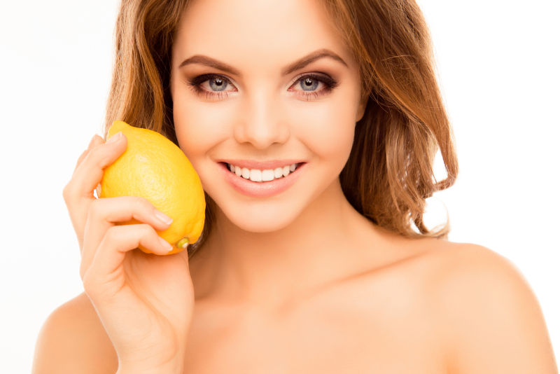 白色背景前拿着柠檬的美女