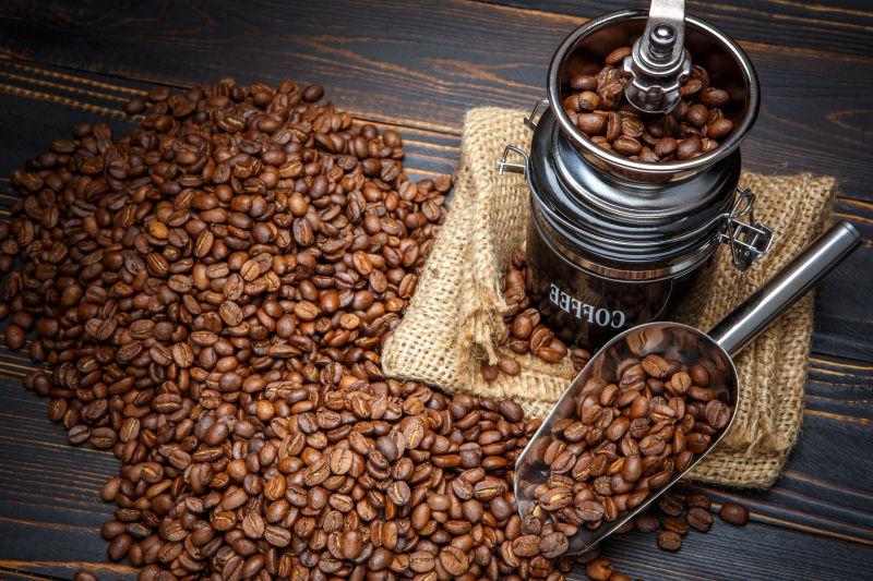 老旧木纹理桌上散落的咖啡豆和咖啡豆机器