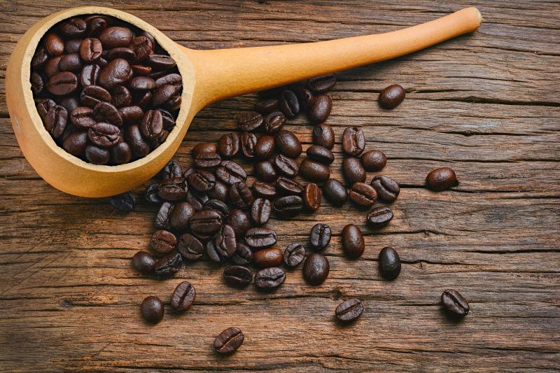 老旧木纹理桌上散落的咖啡豆和木勺子