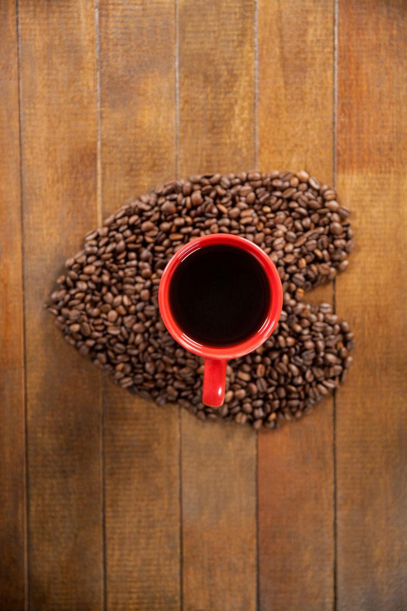木制咖啡桌上有心形咖啡豆与一杯咖啡