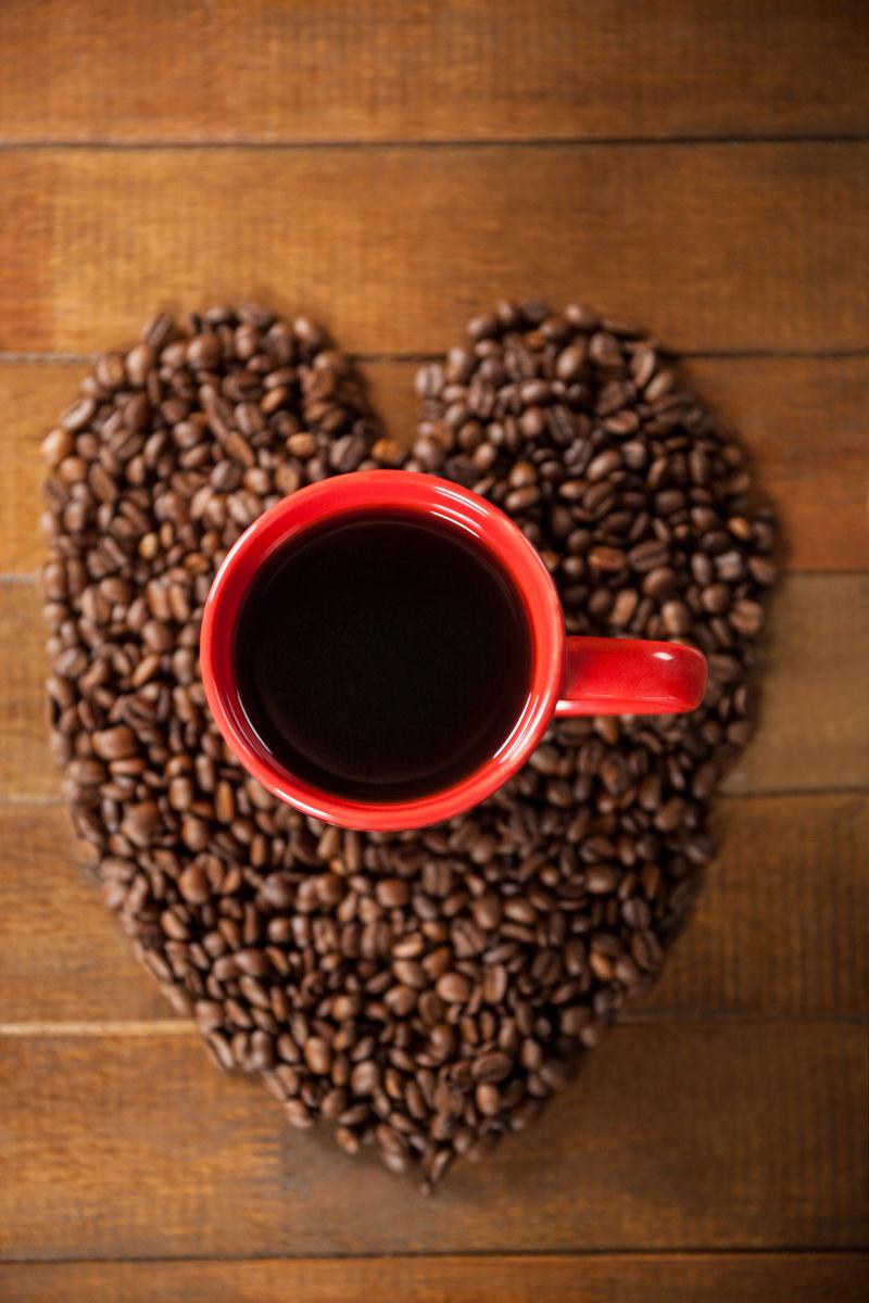 木制咖啡桌上有心形咖啡豆与咖啡