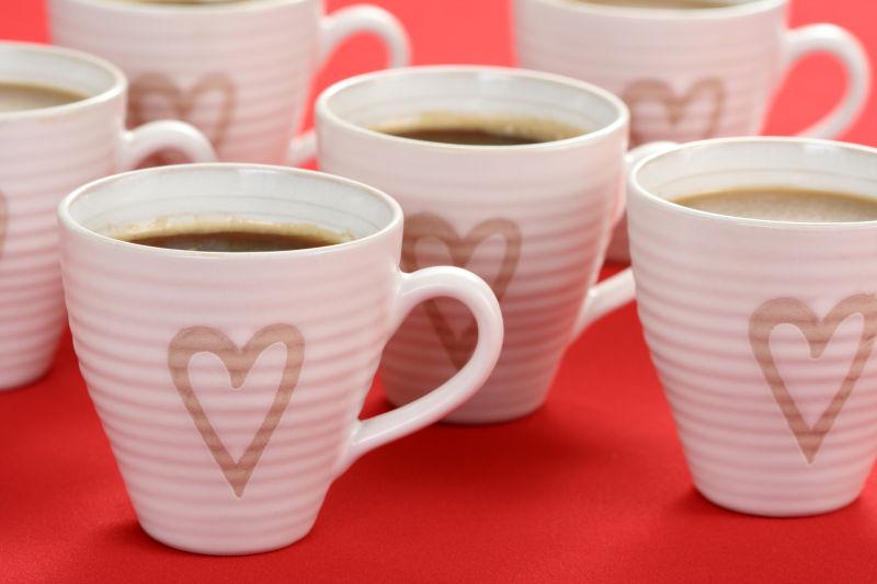 红色桌面上画着爱心的白色咖啡杯