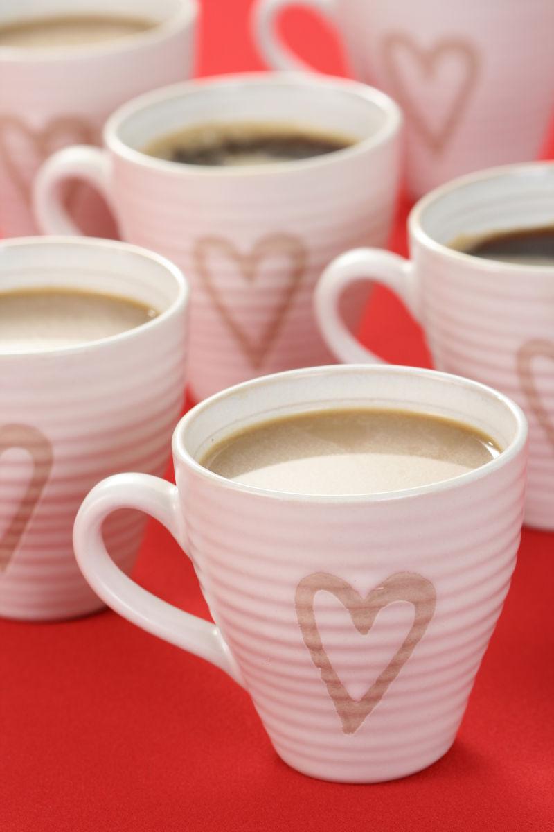 红色桌面上画着爱心的咖啡杯