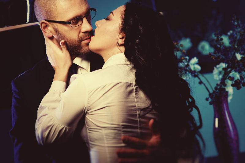 一个性感的黑发女人和英俊的商人在办公室接吻