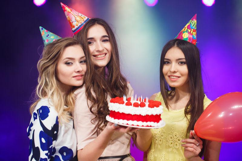 拿着蛋糕的三个年轻美女