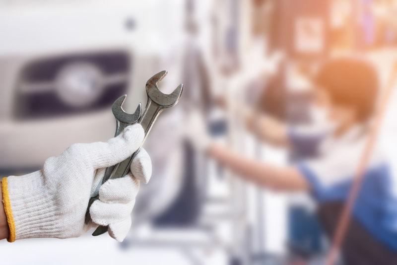 汽车服务中心的工人手拿维修工具