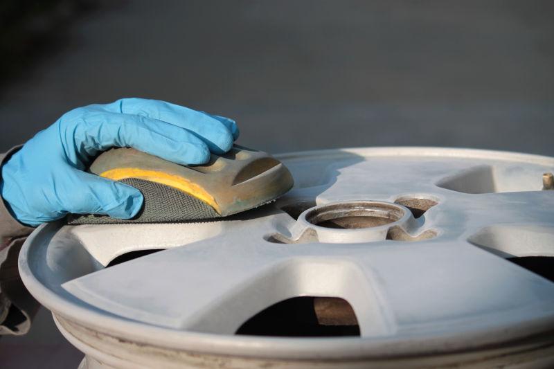 灰色背景上工人手拿刷子清洁汽车轮毂