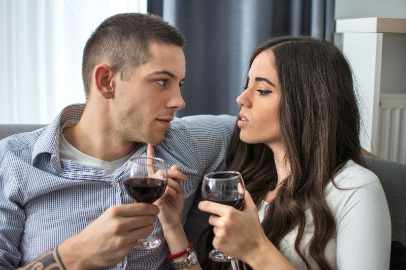 在家里何葡萄酒的年轻女子诱惑男友