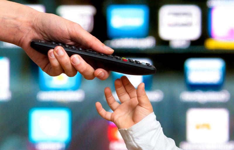 儿童手从父母手中接过遥控器