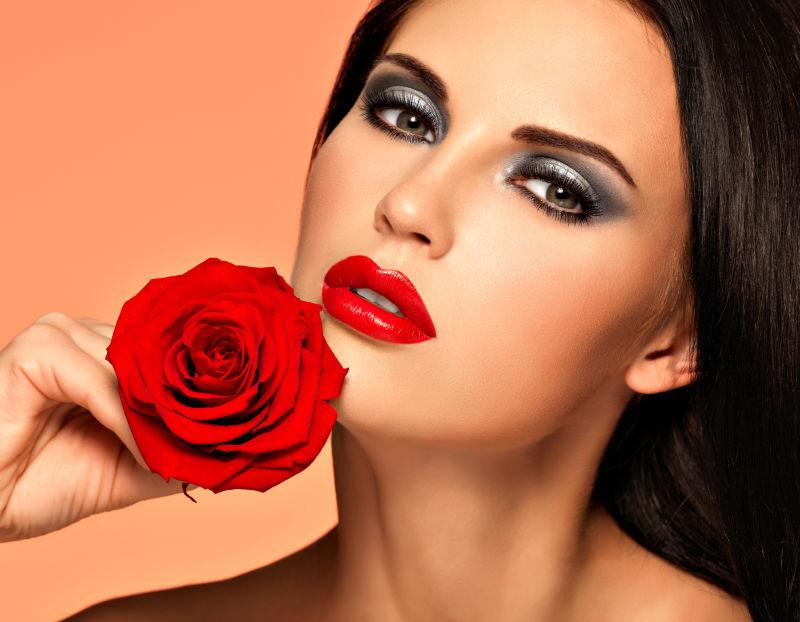 美丽时尚的美丽女人拿着红玫瑰