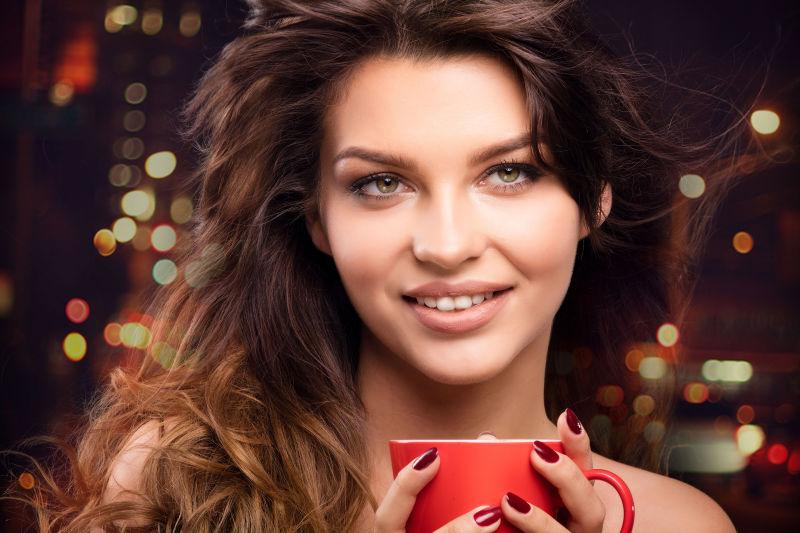 美丽的黑发女人拿着一杯咖啡