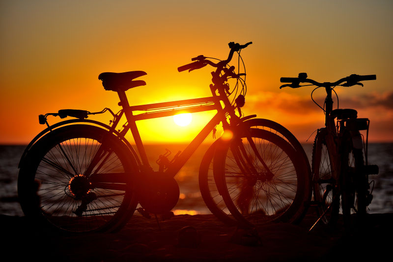 日落海滩下自行车的剪影