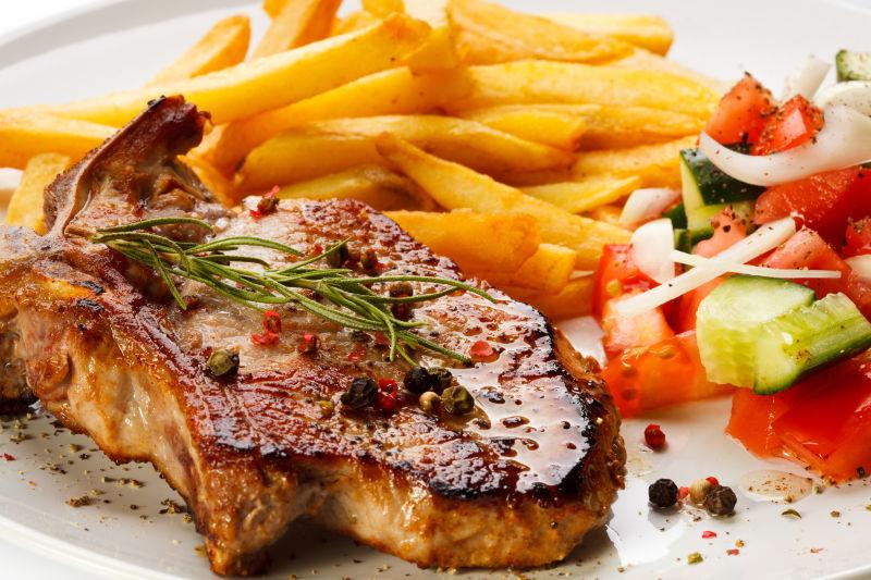 白色盘子上的牛排和薯条还有蔬菜沙拉