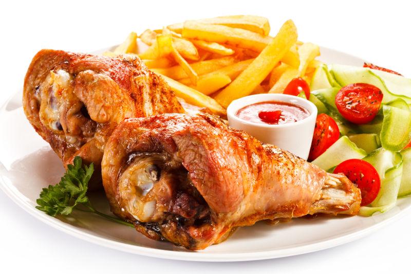 盘子里的鸡腿和薯条还有沙拉