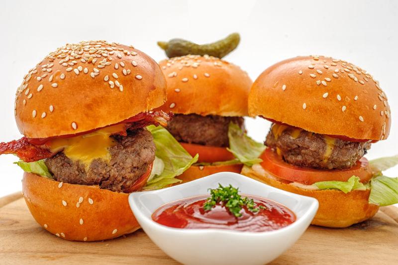 桌子上的三个汉堡和蕃茄酱