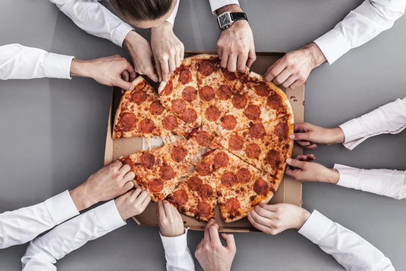 商务团队坐在餐桌旁吃比萨饼