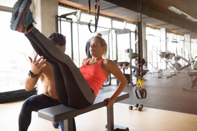 健身房里经教练指导健身的男女