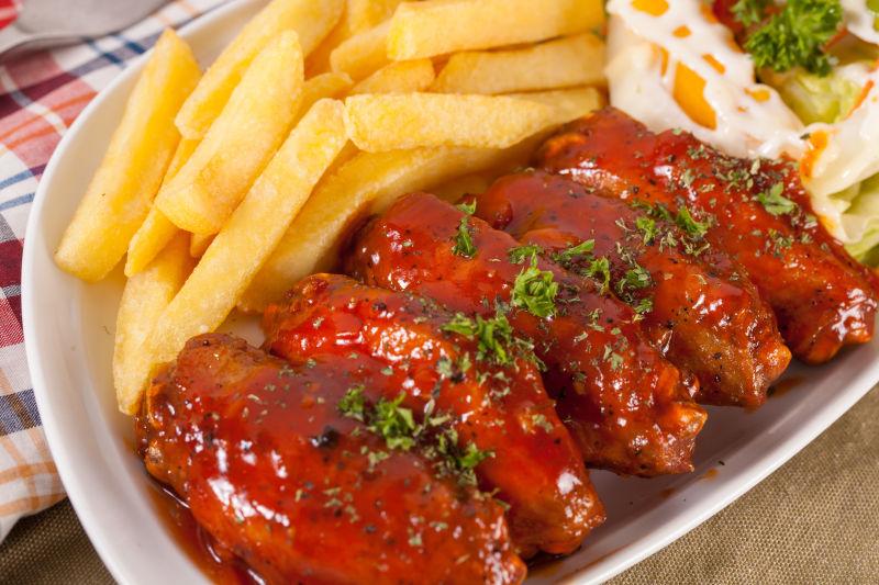 一盘红烧烤酱鸡翅与炸薯条