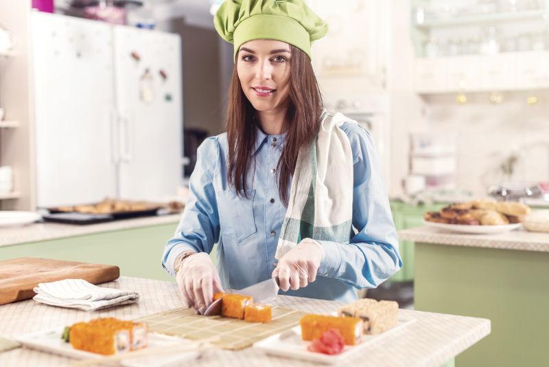 女厨师戴着厨师的帽子和手套做日本寿司卷