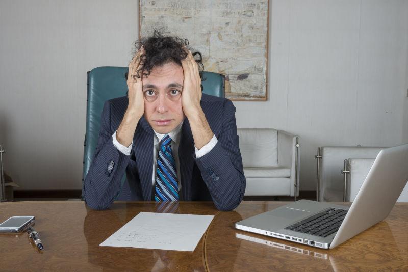 办公桌边抱着脑袋的商业精英