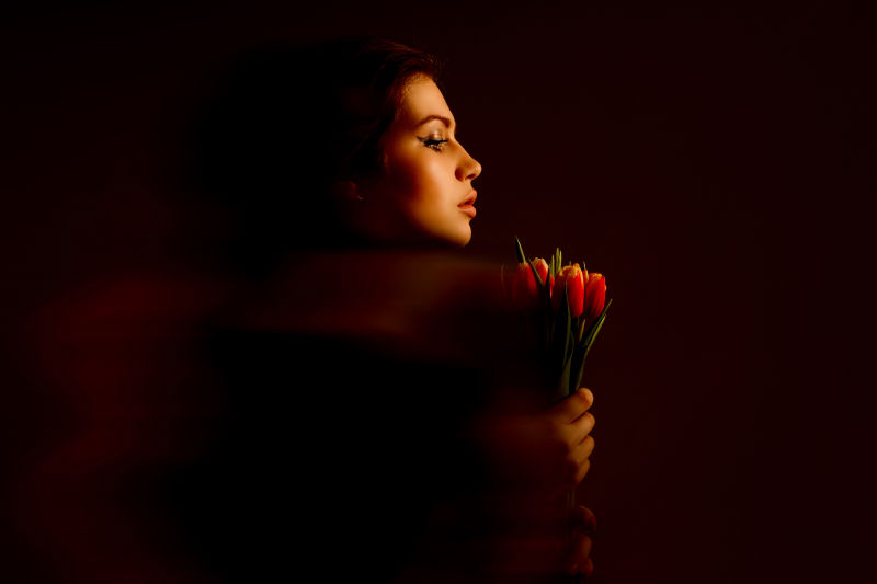 黑暗环境中拿着郁金香的年轻美女