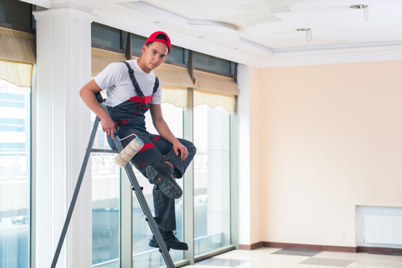 坐在梯子上的帅哥拿着滚筒