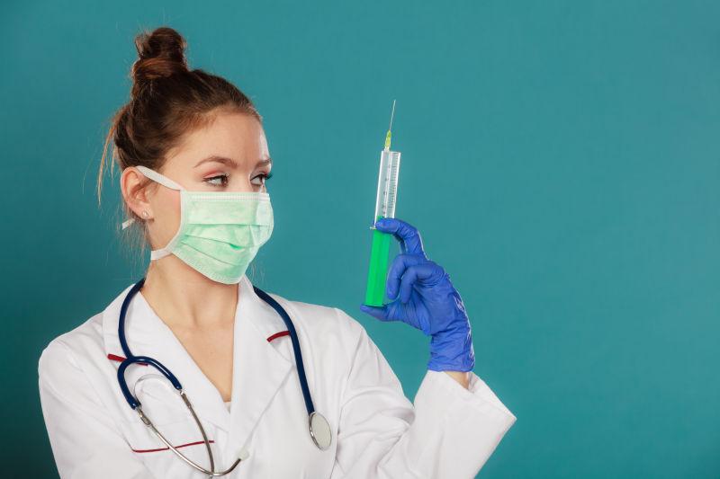 戴着听诊器的年轻的女医生拿着注射器