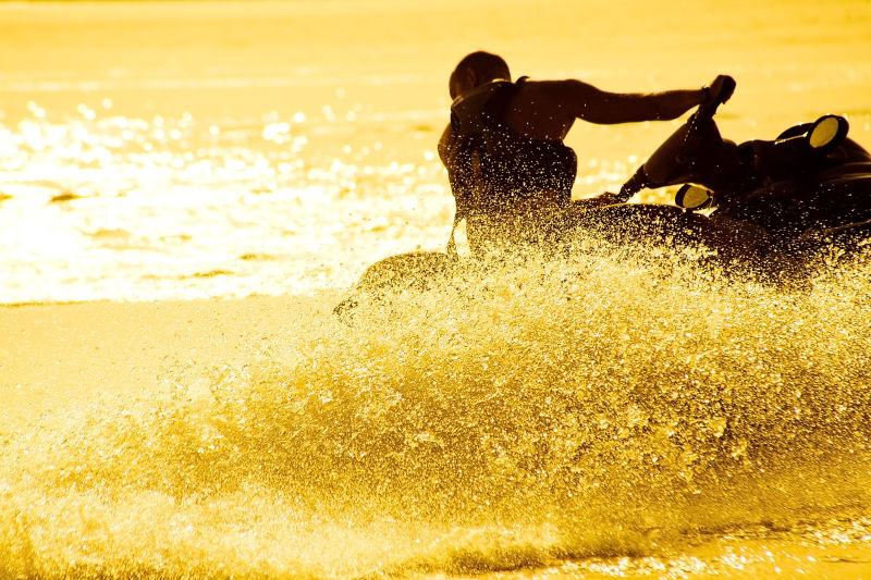 日落时分美丽海面上乘摩托艇的人