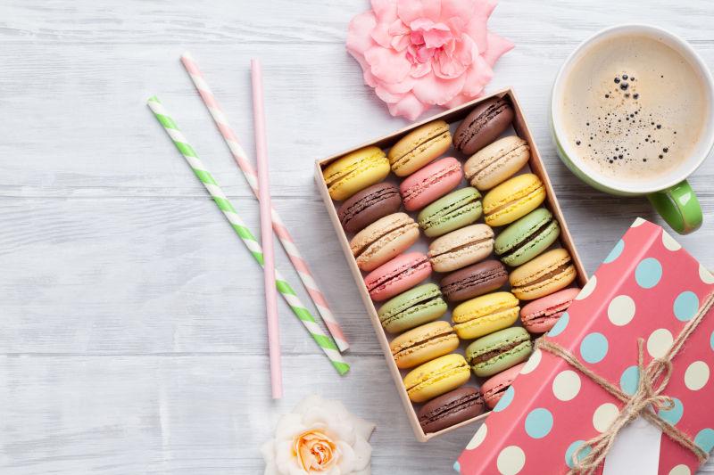 彩盒中的五彩马卡龙和木桌上的咖啡杯