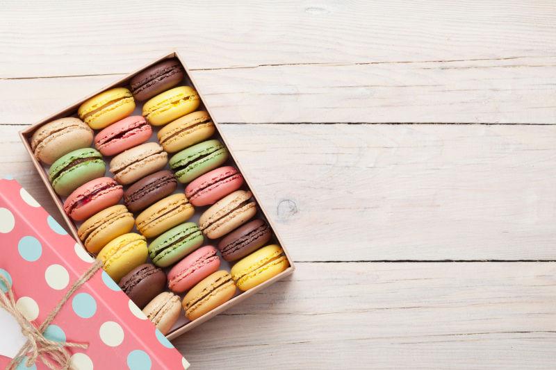 木桌上的马卡龙在彩色盒子里