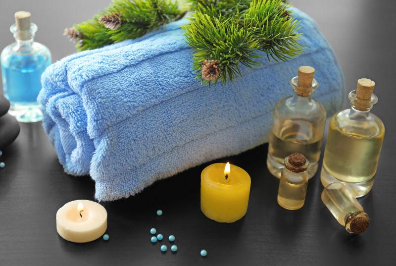 在有蓝色毛巾的桌上的玻璃瓶装护肤品和蜡烛