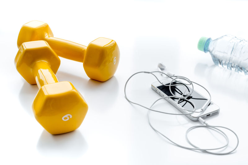 白色背景上的哑铃和手机还有矿泉水