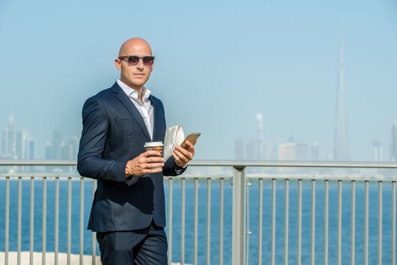 商人手持手机和咖啡